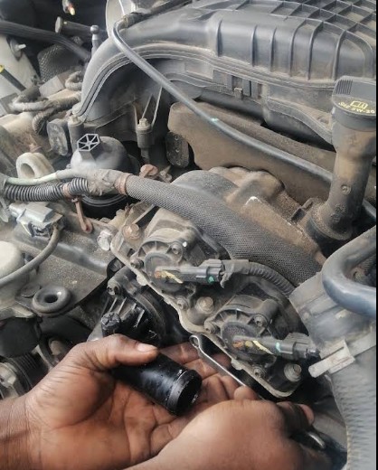 Mechanic replacing an ignition coil inside a car engine bay